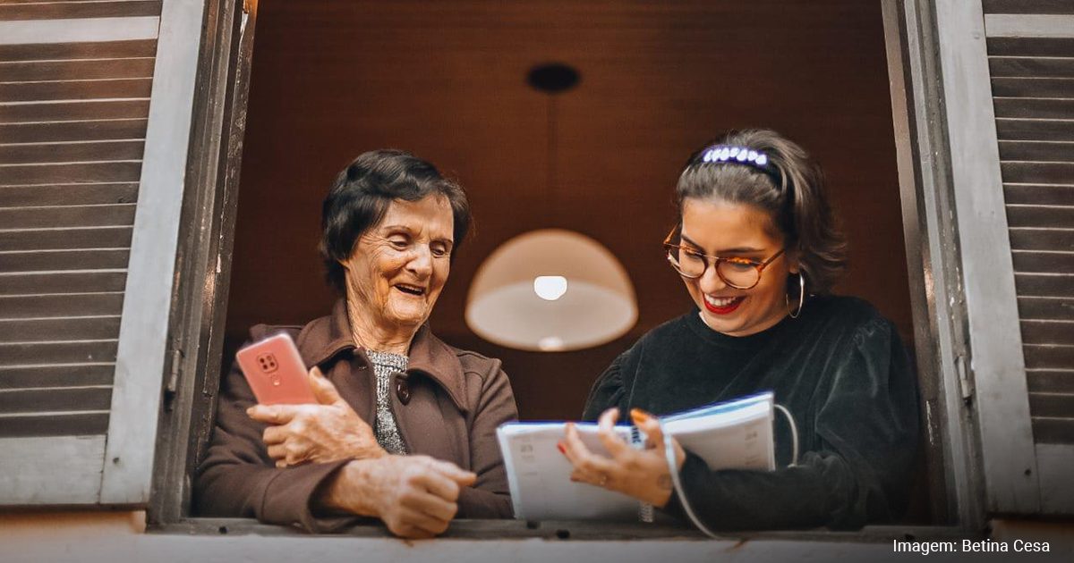 Pessoa usando smartphone com apoio visual em uma janela, simbolizando aplicativos que ajudam na leitura e identificação.