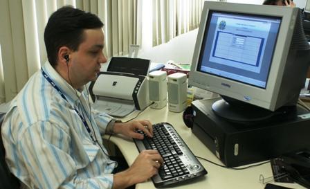 Pessoa usando computador com leitor de tela e fone de ouvido.